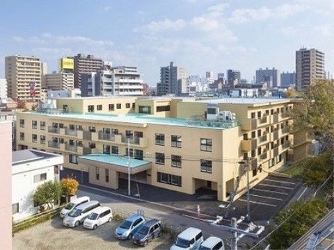 エントランスに車寄せが設けられた外壁がベージュ色の４階建ての施設