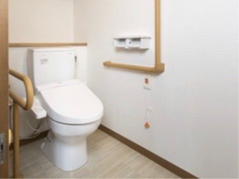 明るいトイレのパーパーホルダーは高い位置に設置されており、入居者様がトイレットペパーを手に取りやすくなっている。