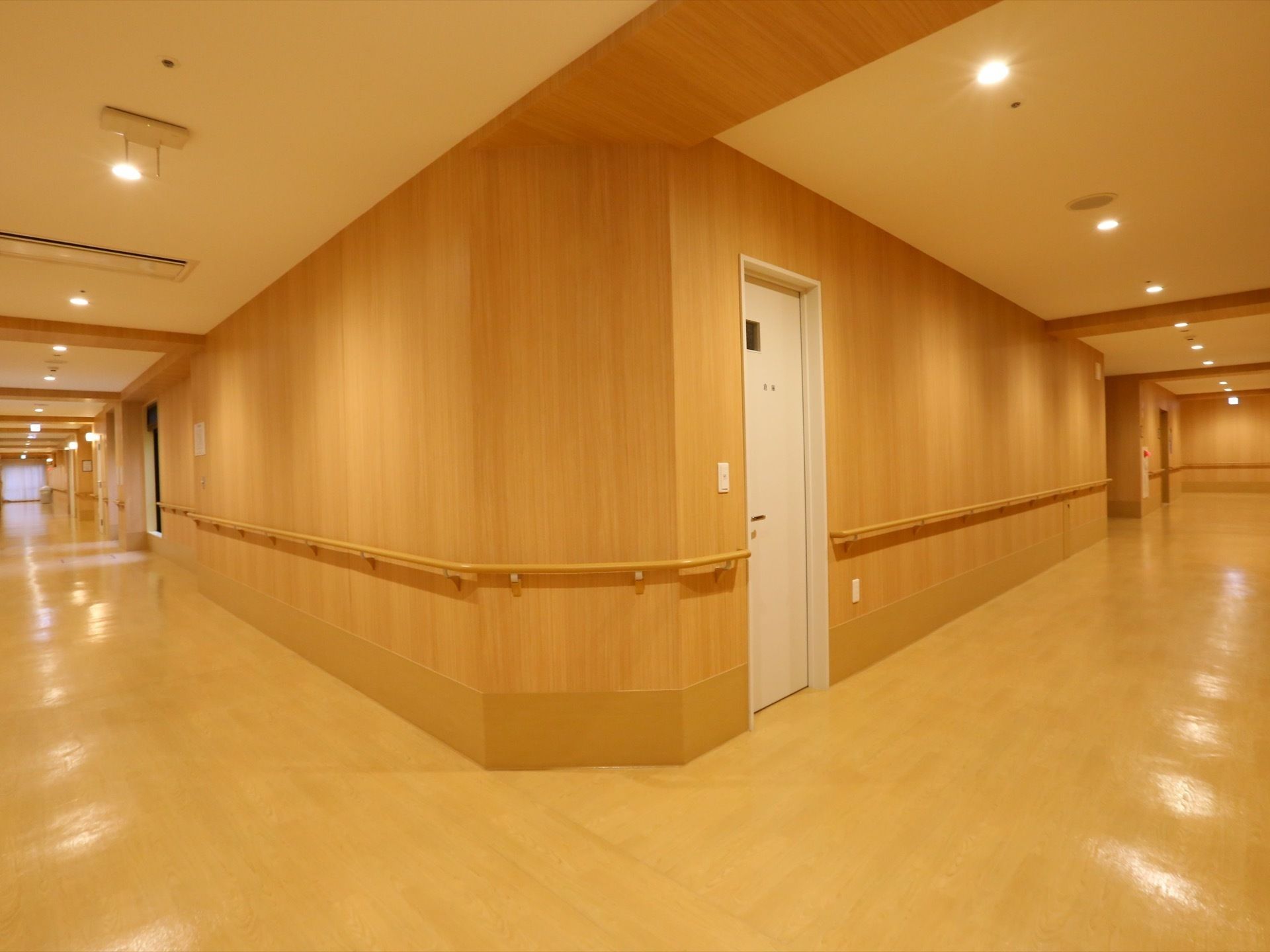 Ｌ字型の通路部分の写真。壁には手すりが設置されており、天井には等間隔で丸い照明が取りつけられている。