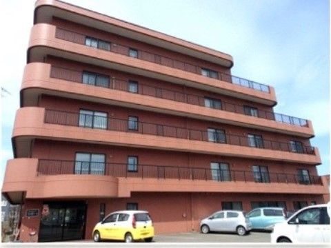 広い駐車場が建物前に設けられている赤茶色の外壁が特徴的な５階建ての施設