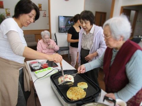 共有スペースで、スタッフと一緒に食事を作っている、入居者様