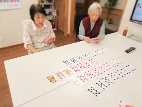 白い大きな机にトランプを複数並べ、遊戯中の入居者様