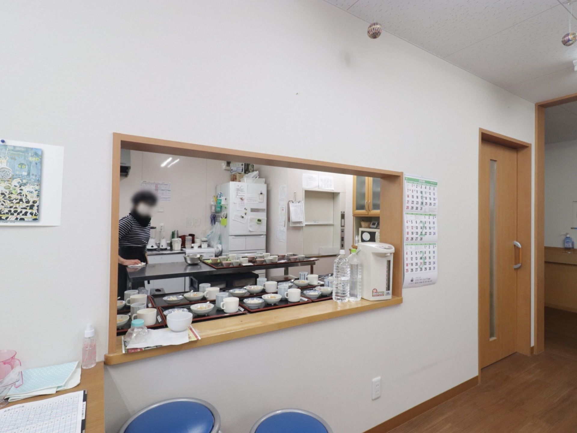 厨房には入居者様の食事を出し入れするカウンターがある。カウンターの上にはポットとペットボトルに入った水が置かれている。