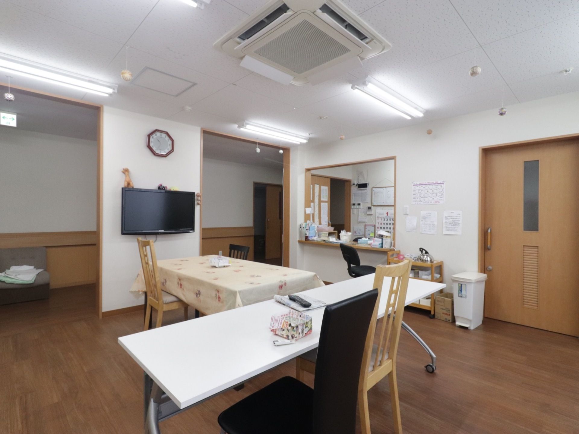 大きなテレビが壁に設置されている。天井にはエアコンがある。食堂と廊下を遮る扉はなく、段差や凹凸がない。