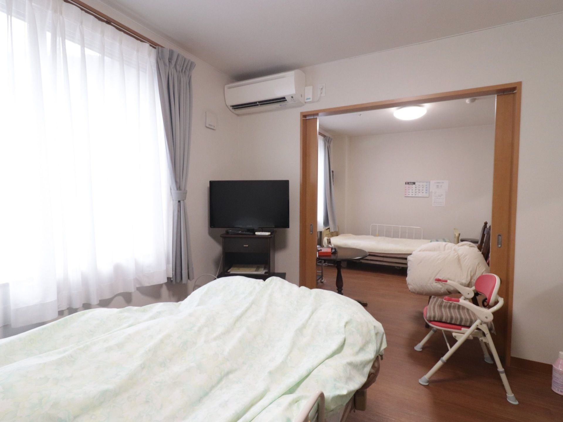 扉を閉めると個室になる。奥の部屋と手前の部屋にベッドが設置されている。テレビとエアコンもある。窓は大きく室内は明るい。