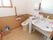 個室の奥に温水洗浄便座を取り付けたトイレがある。右手前に大きな受け皿の流し台があり、ハンドソープや消毒液が置かれている。