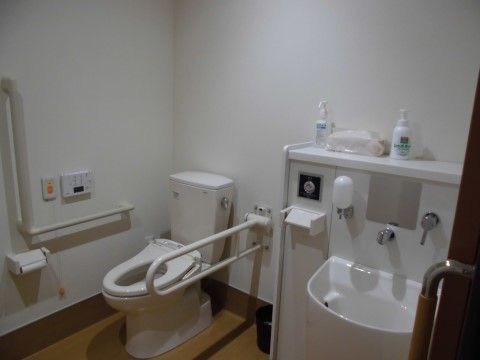 白が基調のゆったりとした空間のあるトイレである。温水洗浄便座や洗面スペース、ナースコール、手すりが完備されている。