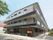 3階建ての施設が建っており、その手前には道路が通っている。玄関の上には屋根があり、雨天時などでも気にせず出入りできる。