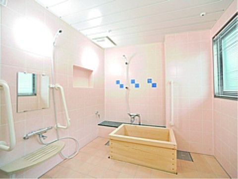 ピンクのタイル張りの壁で、木製の浴槽がある明るい浴室