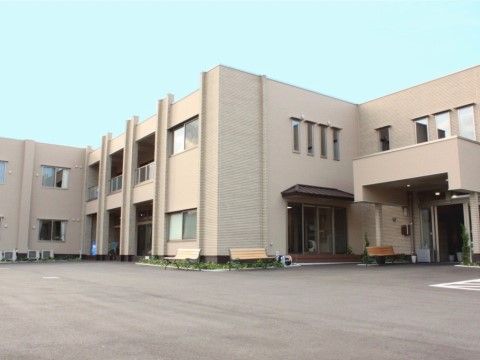施設の建物は２階建てで壁の色はベージュ基調である。玄関には屋根が設置され、周囲には広いスペースが設けられている。