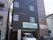 施設は右側が茶色、左側が黒色の外壁となっている。4階建ての建物で、縦長の窓がたくさん取りつけられている。