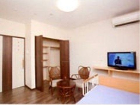 居室の床はフローリングになっており、ベッド、テーブル、手すり付きの椅子、テレビが置かれている。収納スペースも十分に設けられている。