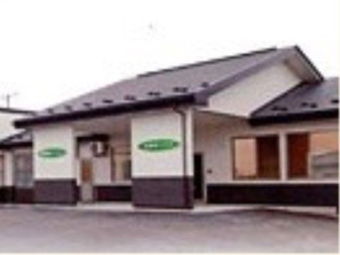 長屋のような白壁に瓦屋根の建物はモダンな雰囲気がある。玄関前は屋根付きになっており、柱に施設名が表示されている。