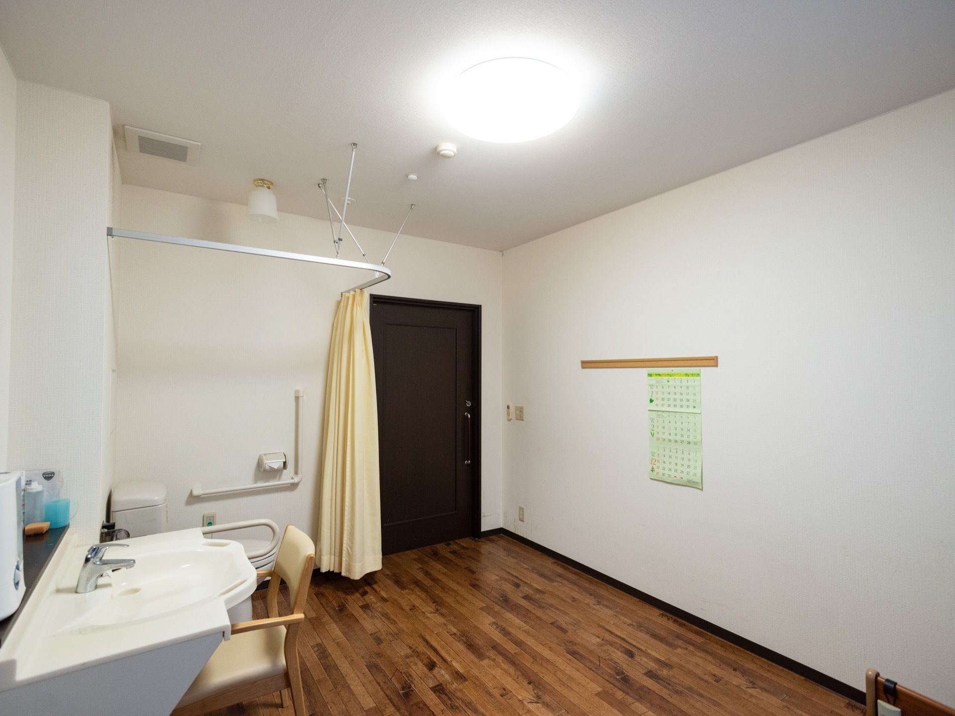 洗面台とカーテンで仕切られたトイレのある居室
