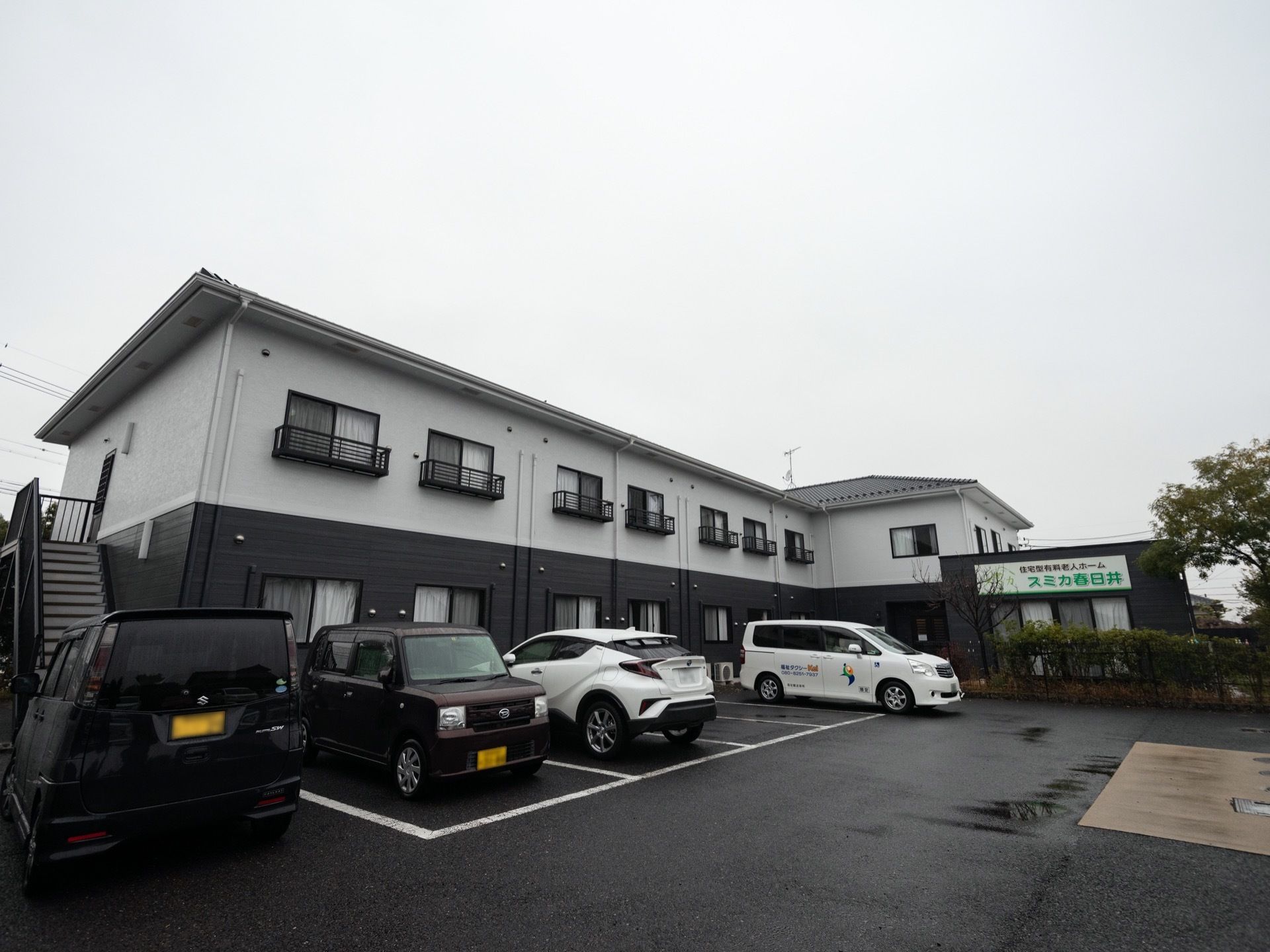 建物前の駐車場に車が停められている高齢者施設の外観
