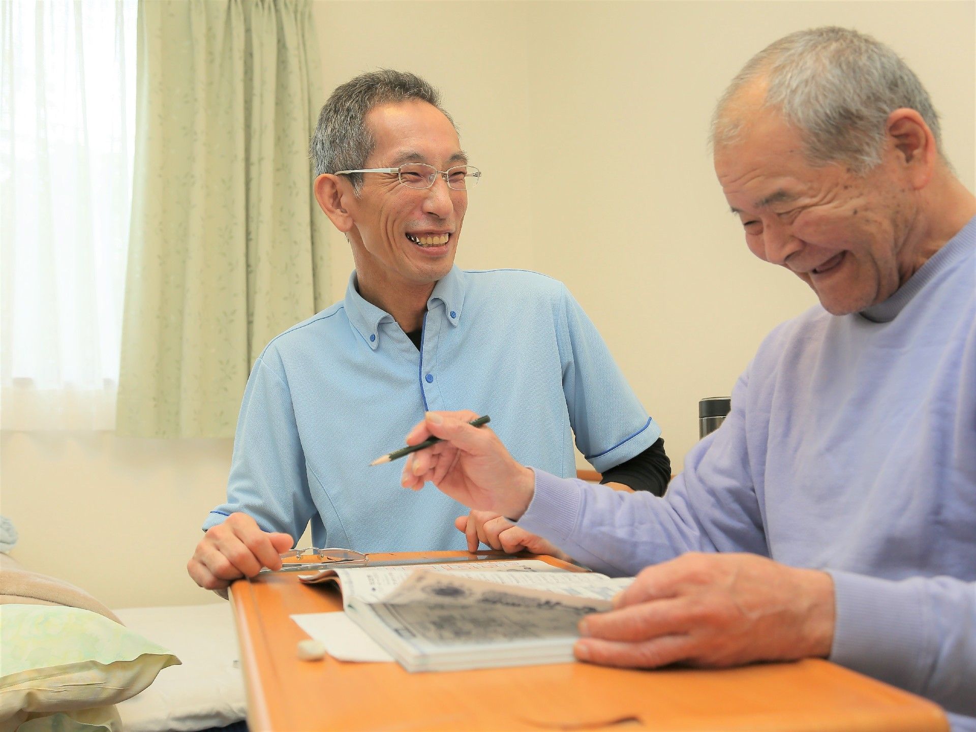 居室にて、男性スタッフとご利用者様が笑顔で話している