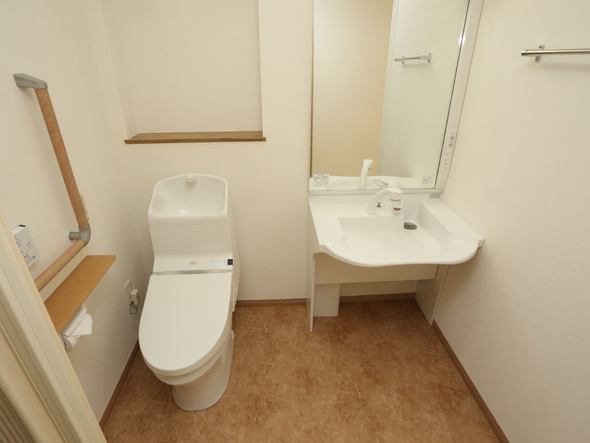 洗面台とトイレが一緒にある。大きな鏡がついて、タオル掛けも取り付けられている。トイレタンクの後ろは棚になっている。