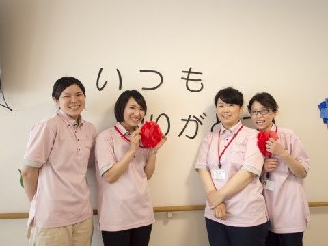 壁に沿って、笑顔で並んでいる４人の施設の女性スタッフ