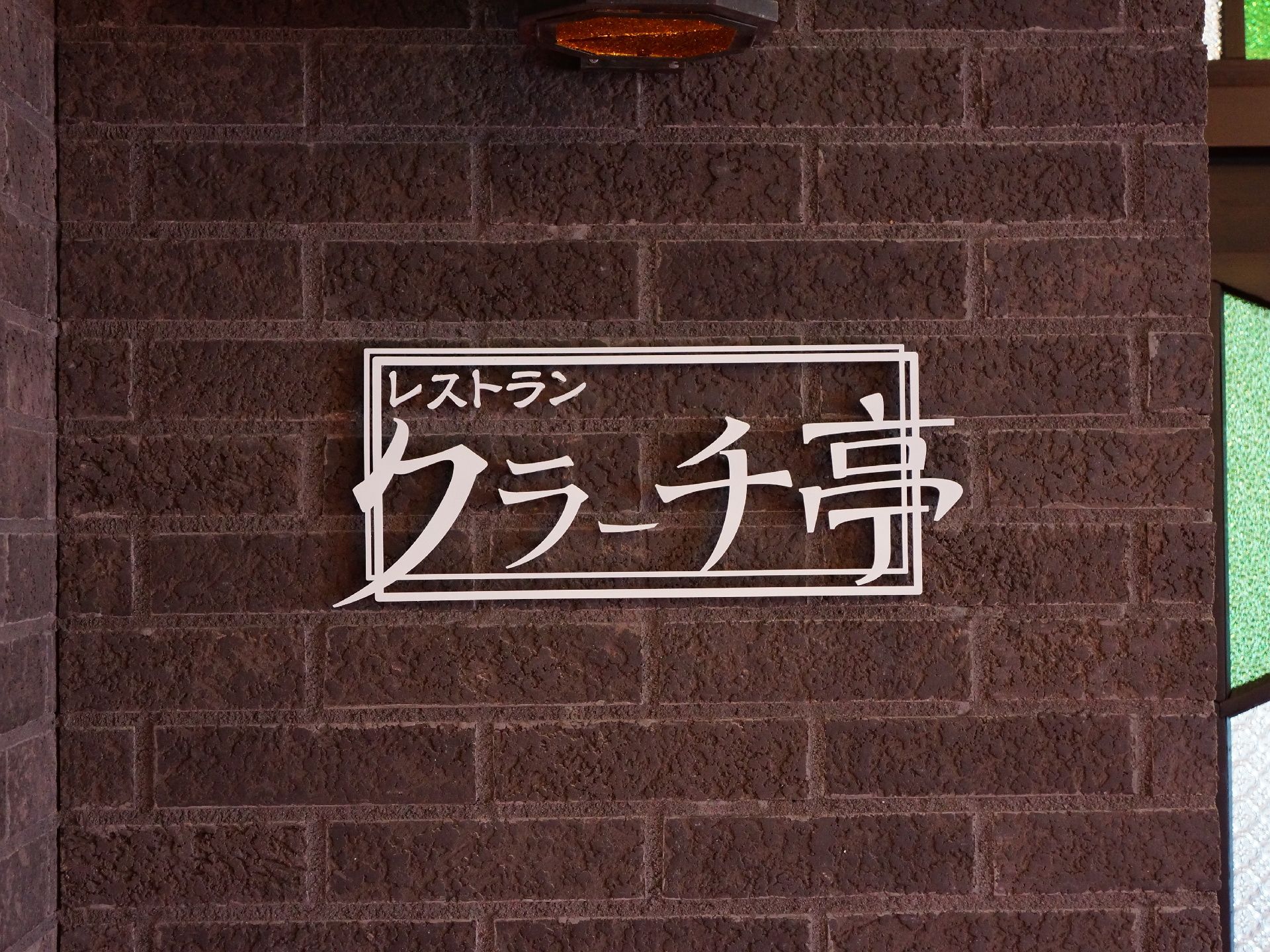 レストランの入り口左側の壁色はダークブラウンである。白い文字で立体的にデザインされたレストラン名が掲げられている。