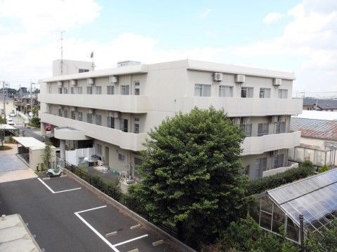 周囲に住宅や畑のある場所にある、鉄筋３階建ての白い建物