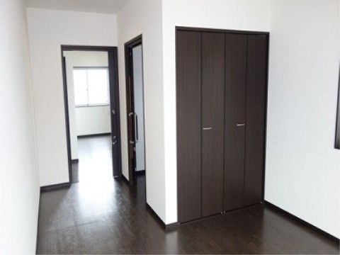 個室タイプの居室にクローゼットが備え付けられている。ダークブラウンと白を基調としたシックな雰囲気の部屋である。