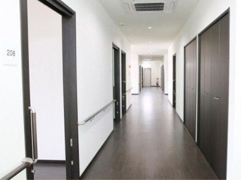 左側には居室が立ち並び、右側には横開きの扉が付いた収納スペースがある。壁には手すりが設置されている。