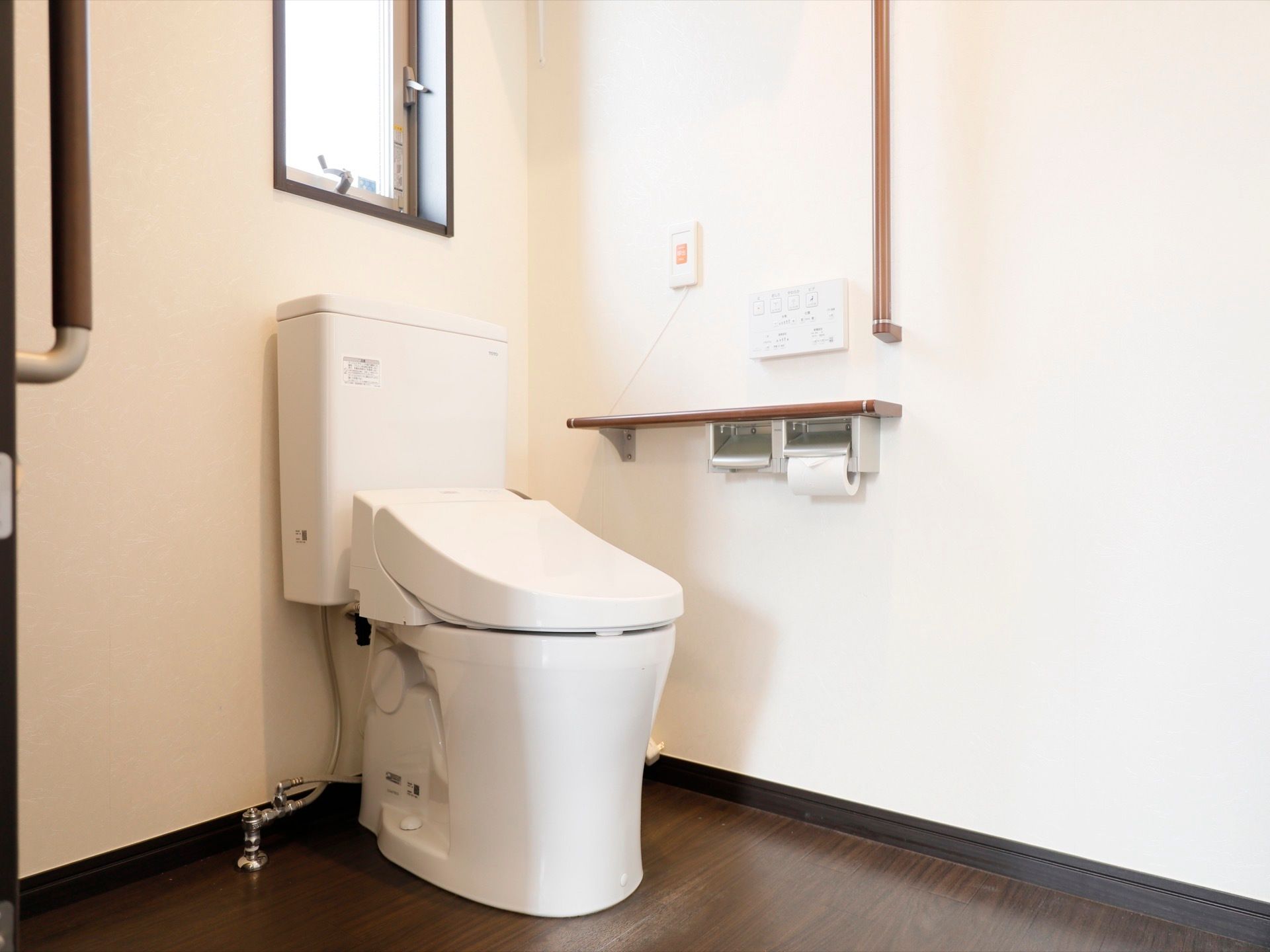 窓があるトイレなので明るく、手軽に換気ができる。壁には手すり、緊急時コールボタンが付いており、安全面にも気を配っている。