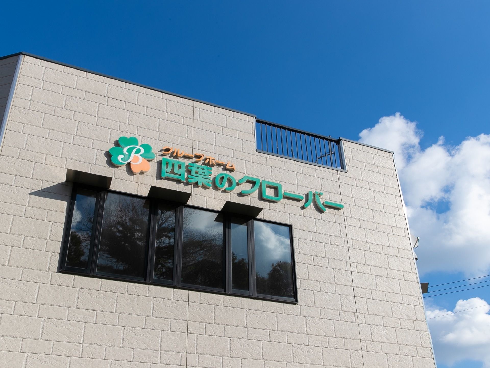 ホームの外壁に施設名が大きく書かれている。屋上部分には転落防止のため、黒いフェンスが設置されている、