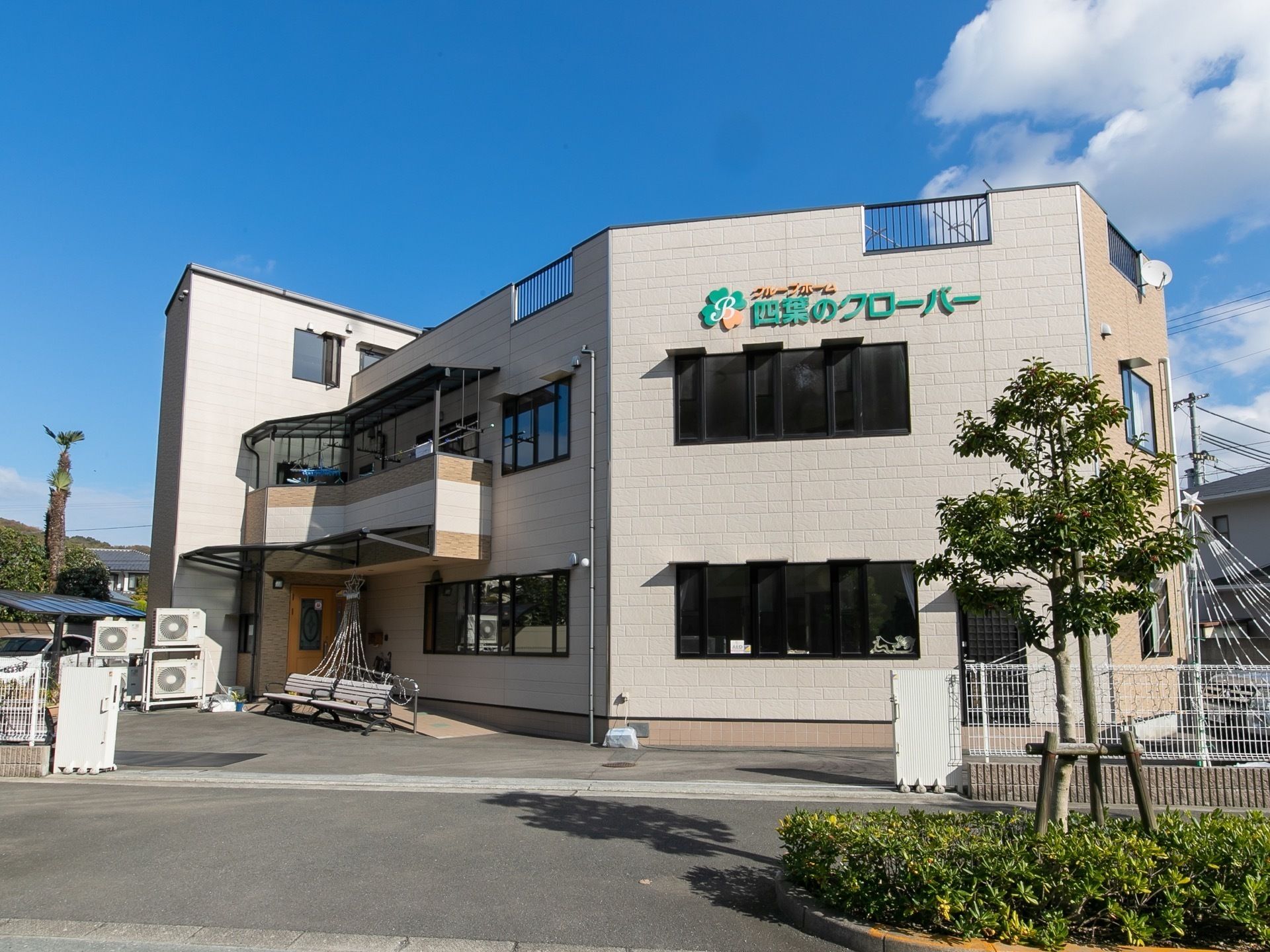 木に囲まれた場所にある花畑で、微笑んでいる黒の上着を着た男性