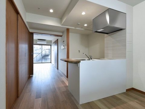 木目調の床に白色を主体としたデザインのオープンなキッチン