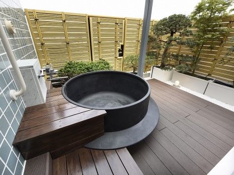 木製の垣根に囲まれたスペースに設置された大きな釜の形をした浴槽