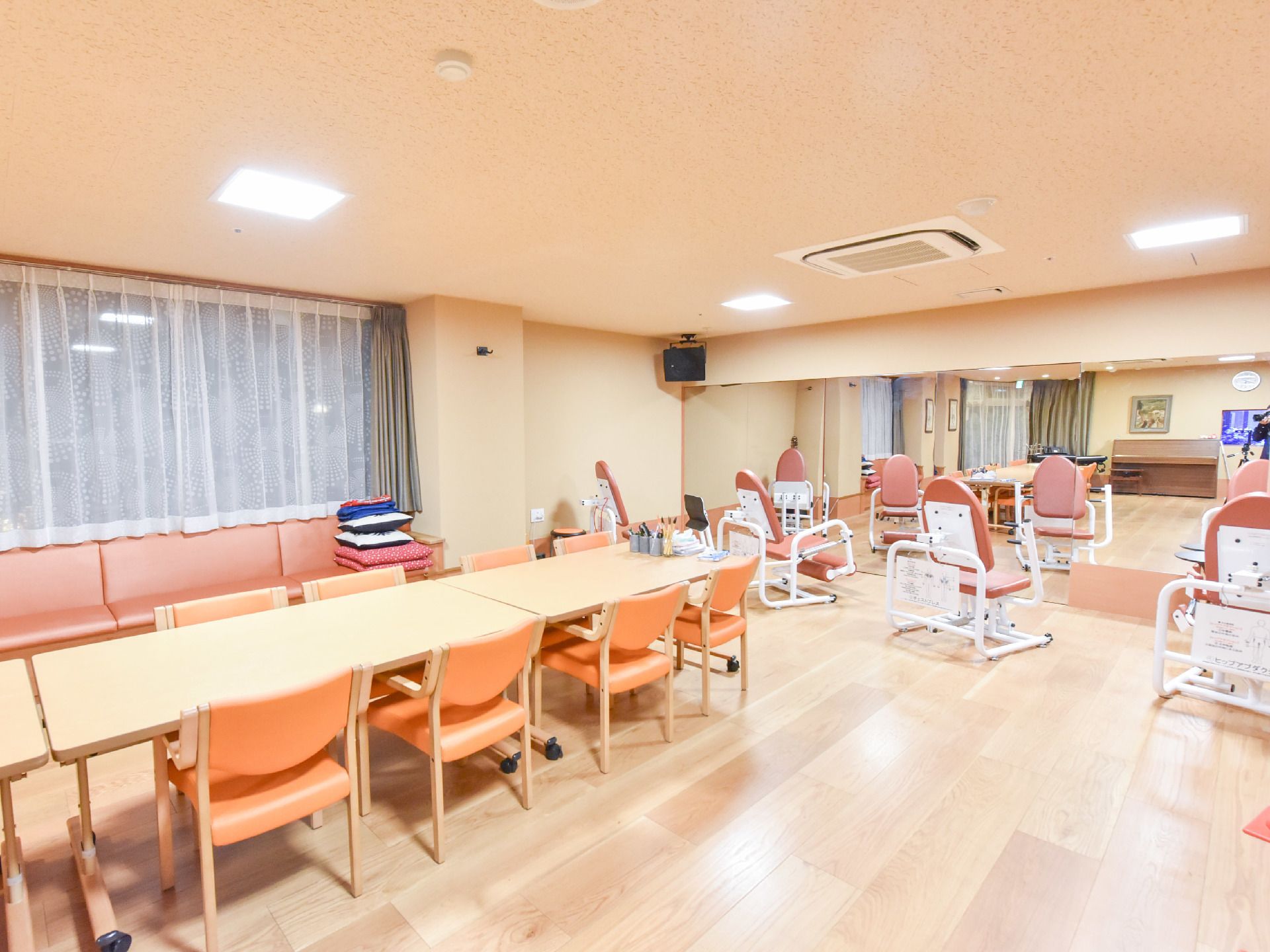 室内の一番奥には、4つの椅子と壁一面の大きな鏡が設置されている。壁際には横長のソファーが壁付けされています。