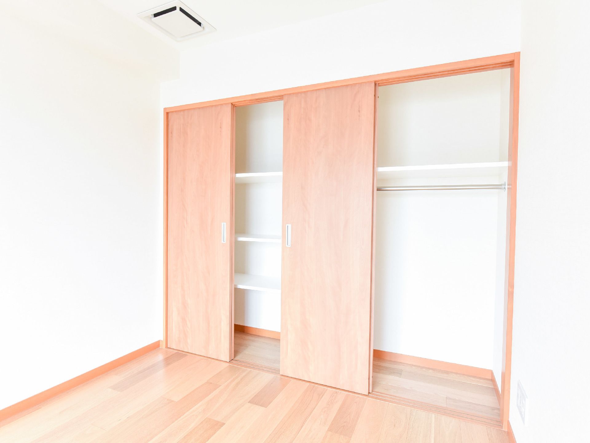 空調が屋根についている。開き扉がついた二間分の収納が設けてある。中には白い棚がある。衣類を収納できるハンガーポールがある。