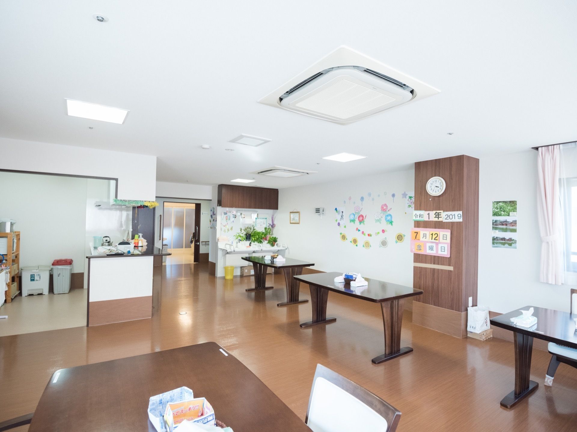 食堂に、角が取れた天板のテーブルが置かれている。キッチンはオープンカウンターで、食堂への通路が広く確保されている。