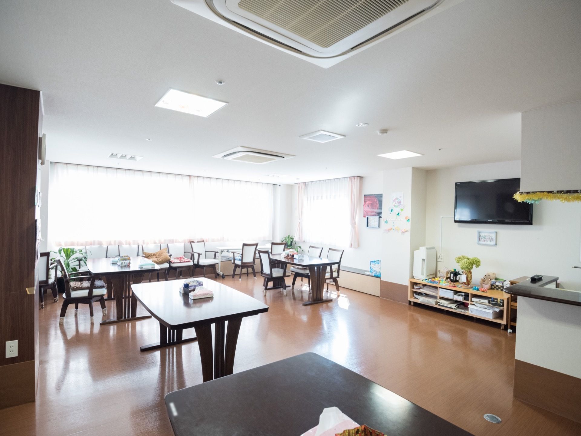 大きな窓が２面にあってとても明るい食堂である。キッチンの近くの壁の上の方に、大画面のテレビが掛けられている。