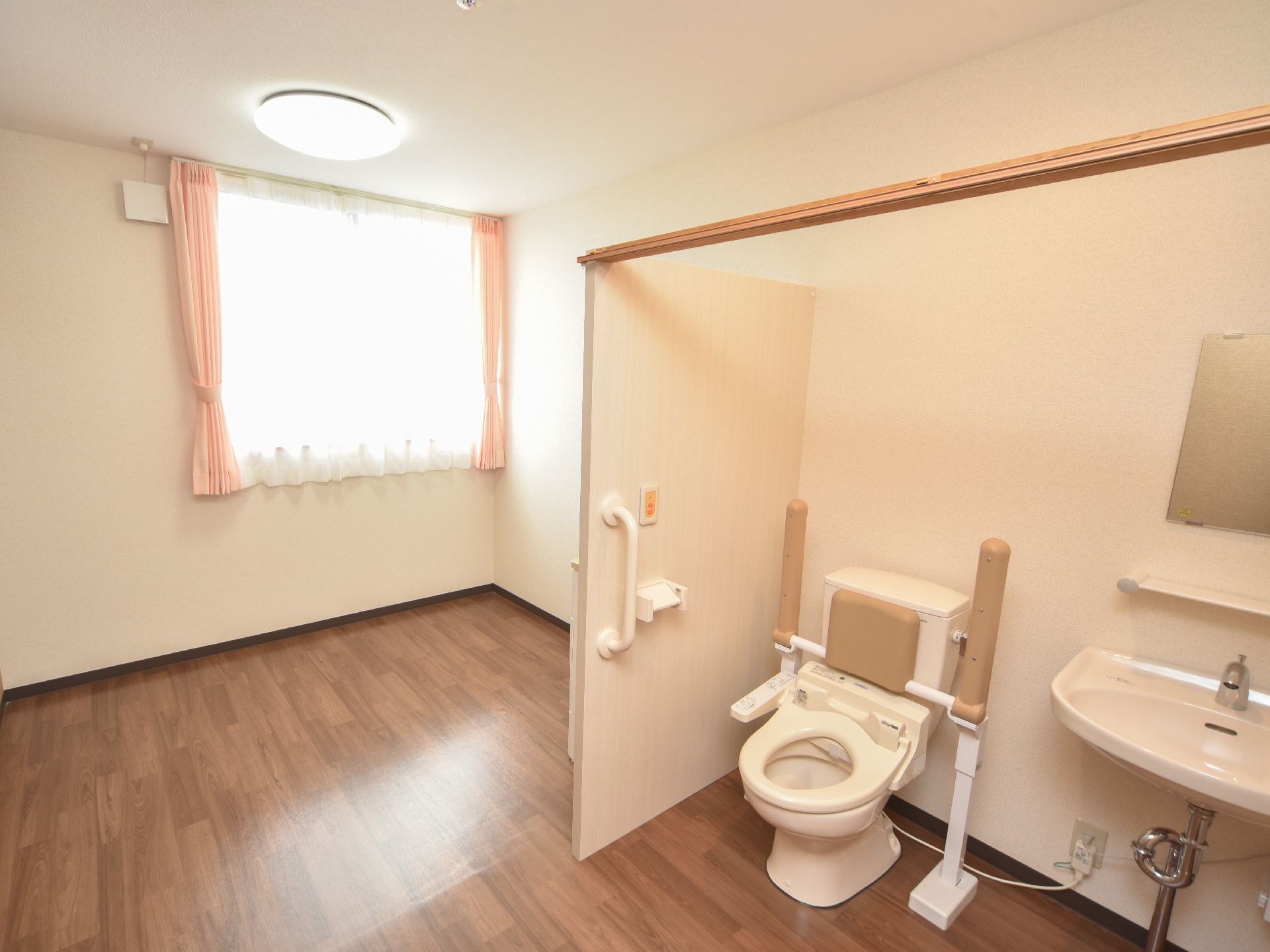 トイレと洗面台が取り付けられているスペースは、ドアが付いていない構造となっている。前方にカーテンレールが設置されている。