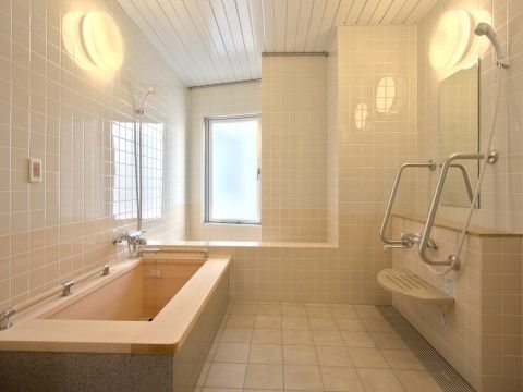 窓が付いた明るい浴室である。洗い場に設置された鏡の両サイドには、しっかりとした手すりが取り付けられている。