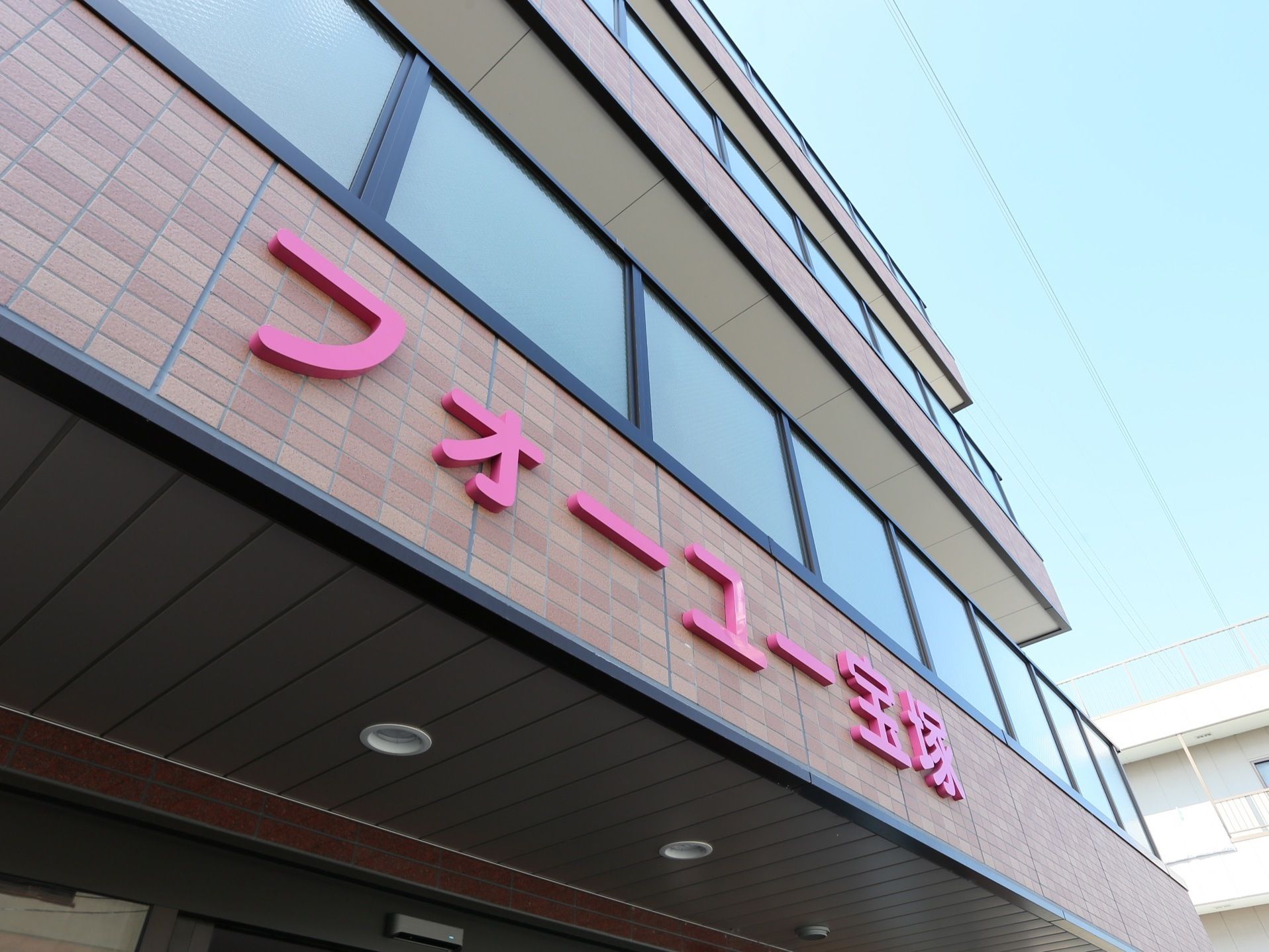 ひさしの部分の外壁には茶色のタイルが貼られている。ベランダには、ポリカーボネート製の手すりが設置されている。