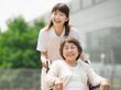 笑顔で車椅子に乗る高齢女性と介助をする女性ヘルパー