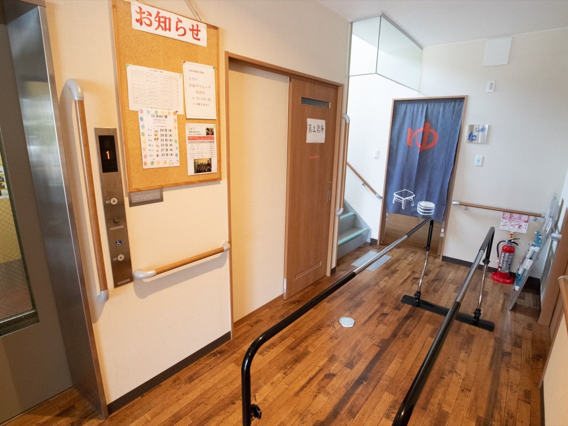 エレベーターが設置されており、昇降ボタンは低い位置からも押しやすくなっている。壁にお知らせが貼られている。