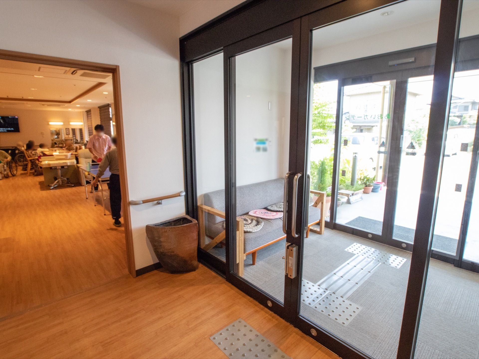 施設の玄関は二重扉になっており風除室になっている。奥に写っている部屋は広く、卓球をしている入居者様もいる。