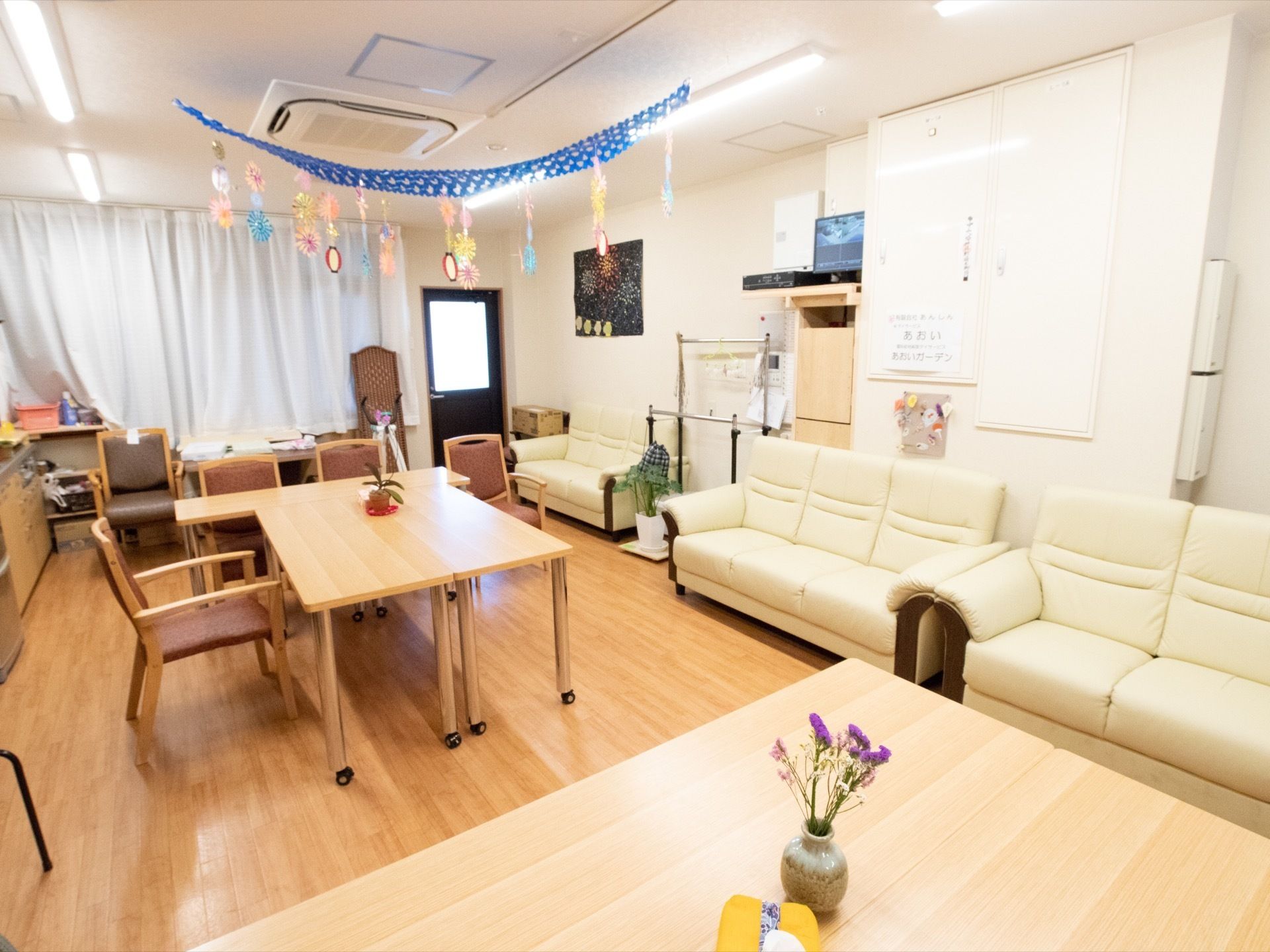 リビングルームにはテーブルや椅子が並べられており、ソファも用意されている。天井には飾りつけがされている。