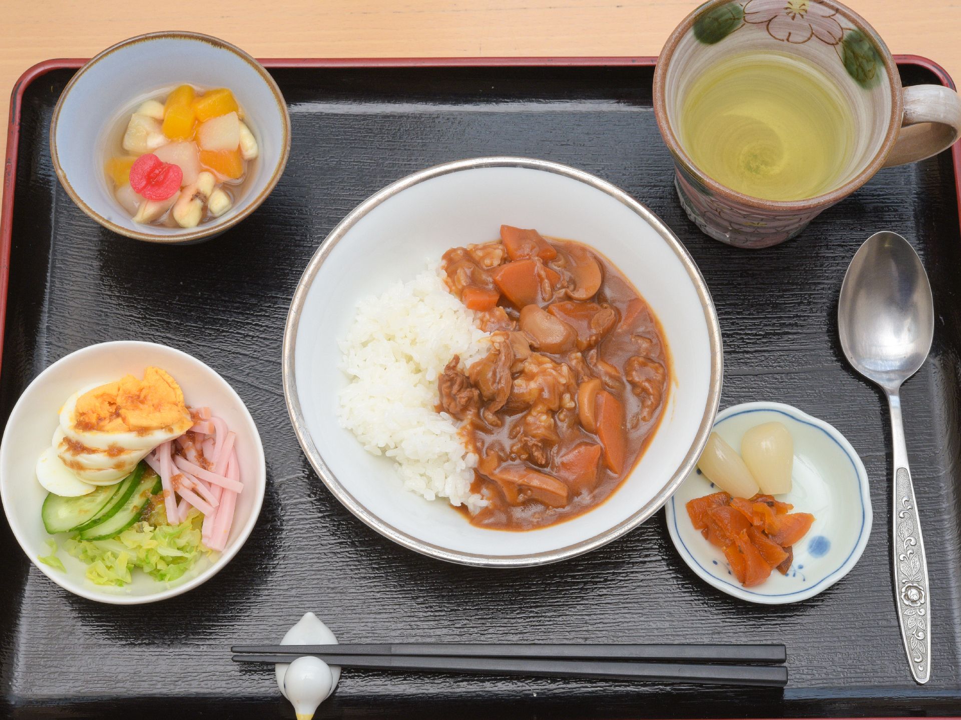 トレーの中央にカレーが、その周りにサラダや福神漬けなどが並ぶ。