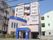 建物の周辺には、マンションが建ち並んでいる。建物は薄いベージュ色でところどころ、濃い青色で縁取られている。