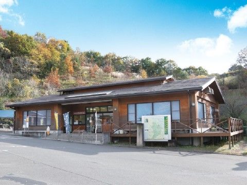 山肌に映える紅葉を背に、越屋根のある木造の平家がある。入口ガラスの両脇にも大きな窓があり、ウッドデッキもある。