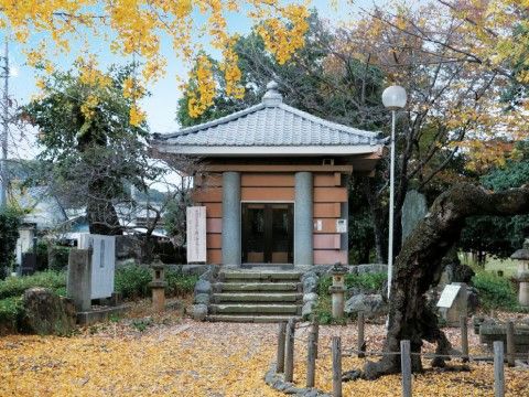 落ち葉で覆いつくされた敷地に、古碑の納められた現代的な建物がある。趣のある老木や案内札、新しい石碑もある。