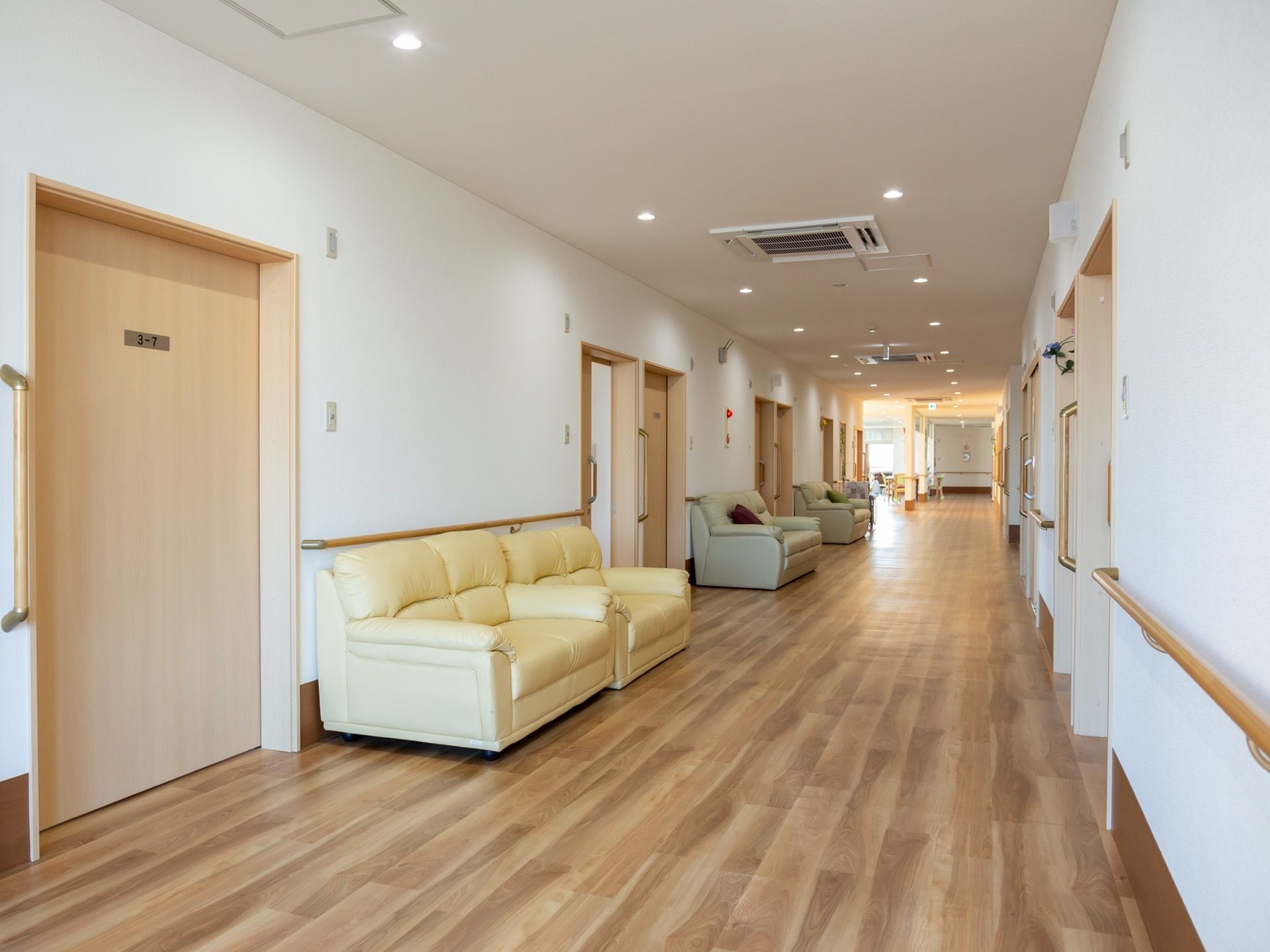 広々とした廊下に、ソファが多数置かれている。居室の扉は、大きめの引き戸で、壁には手すりも取りつけてある。