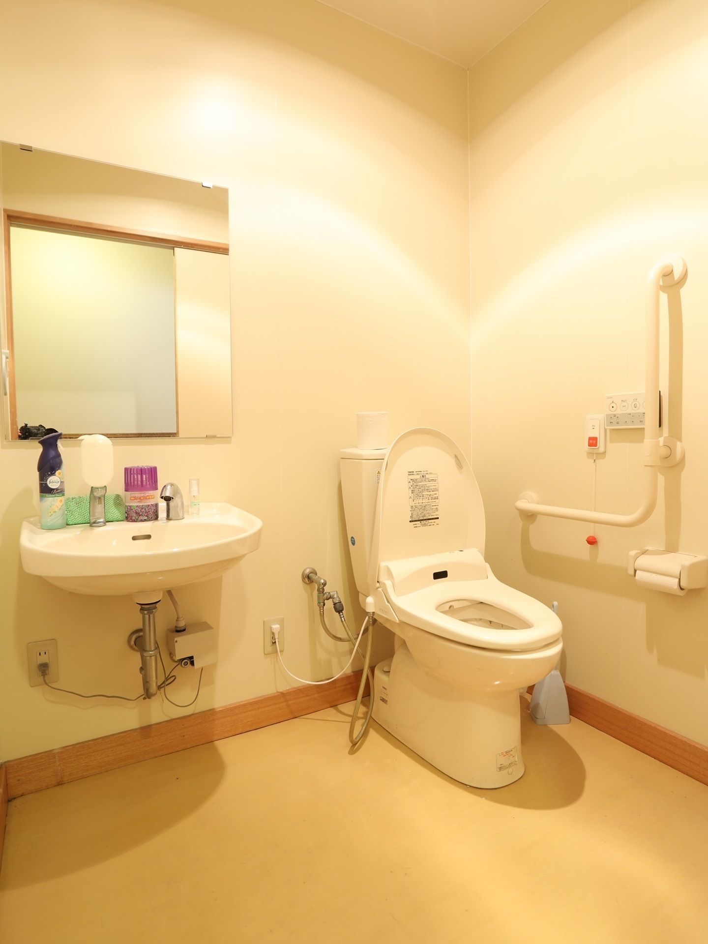 洗面台と鏡の完備されたトイレスペースである。トイレの近くには、手すりと呼び出しベルが備えられている。