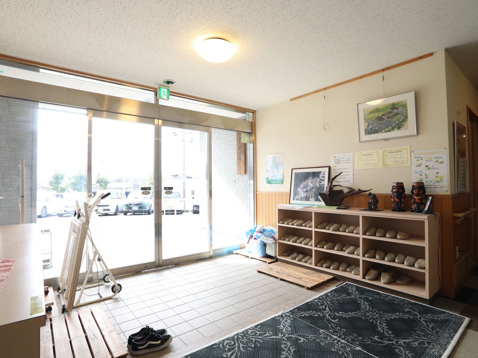 綺麗にスリッパの並べられた靴棚の上には、木製の工芸品が飾られている。また、歩行補助器が備えられている。