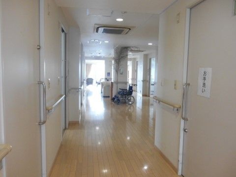 壁には手すりが付けられ奥に車椅子が置かれた廊下